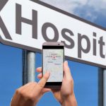 hospital sign with a phone in hand
